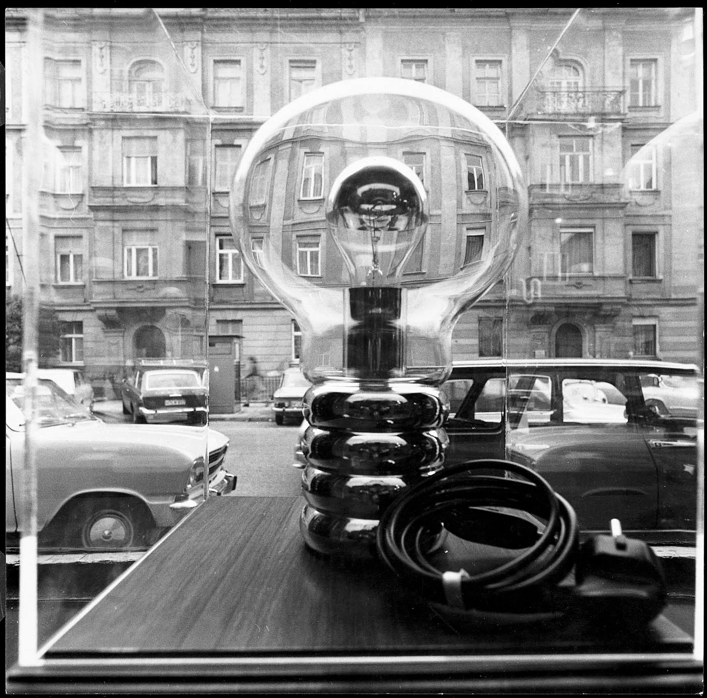 Black-and-white photograph of a bulb lamp in a window, from the Ingo Maurer Munich showroom page