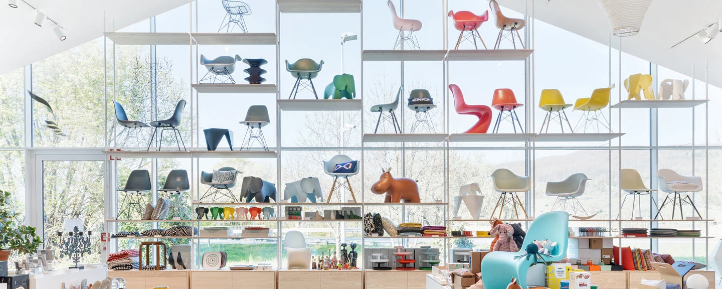 Shelves filled with Vitra chairs and objects in colourful finishes