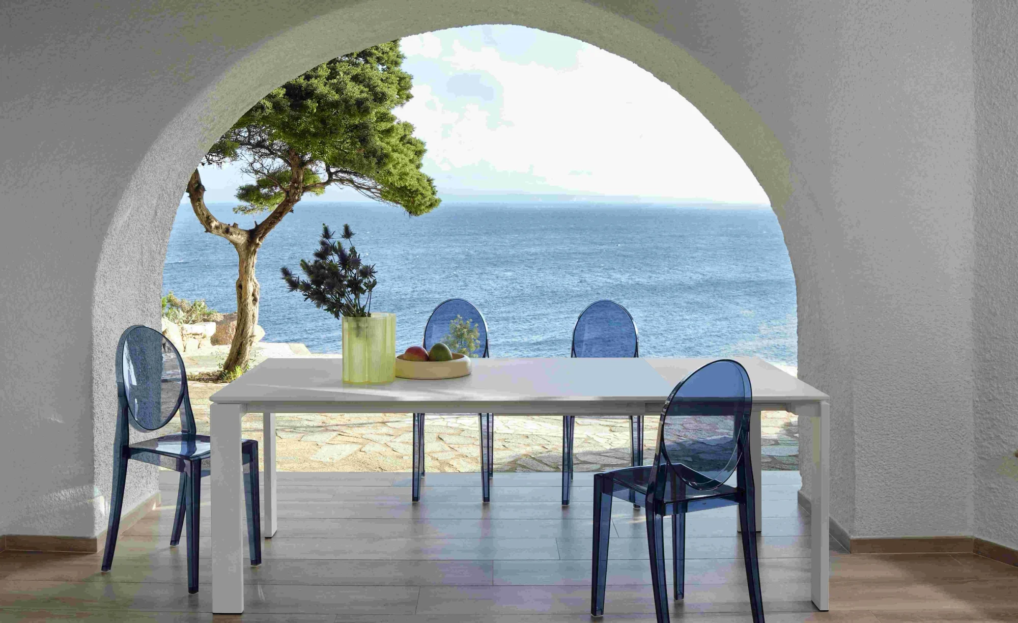 Kartell transparent chairs at a dining table by the sea