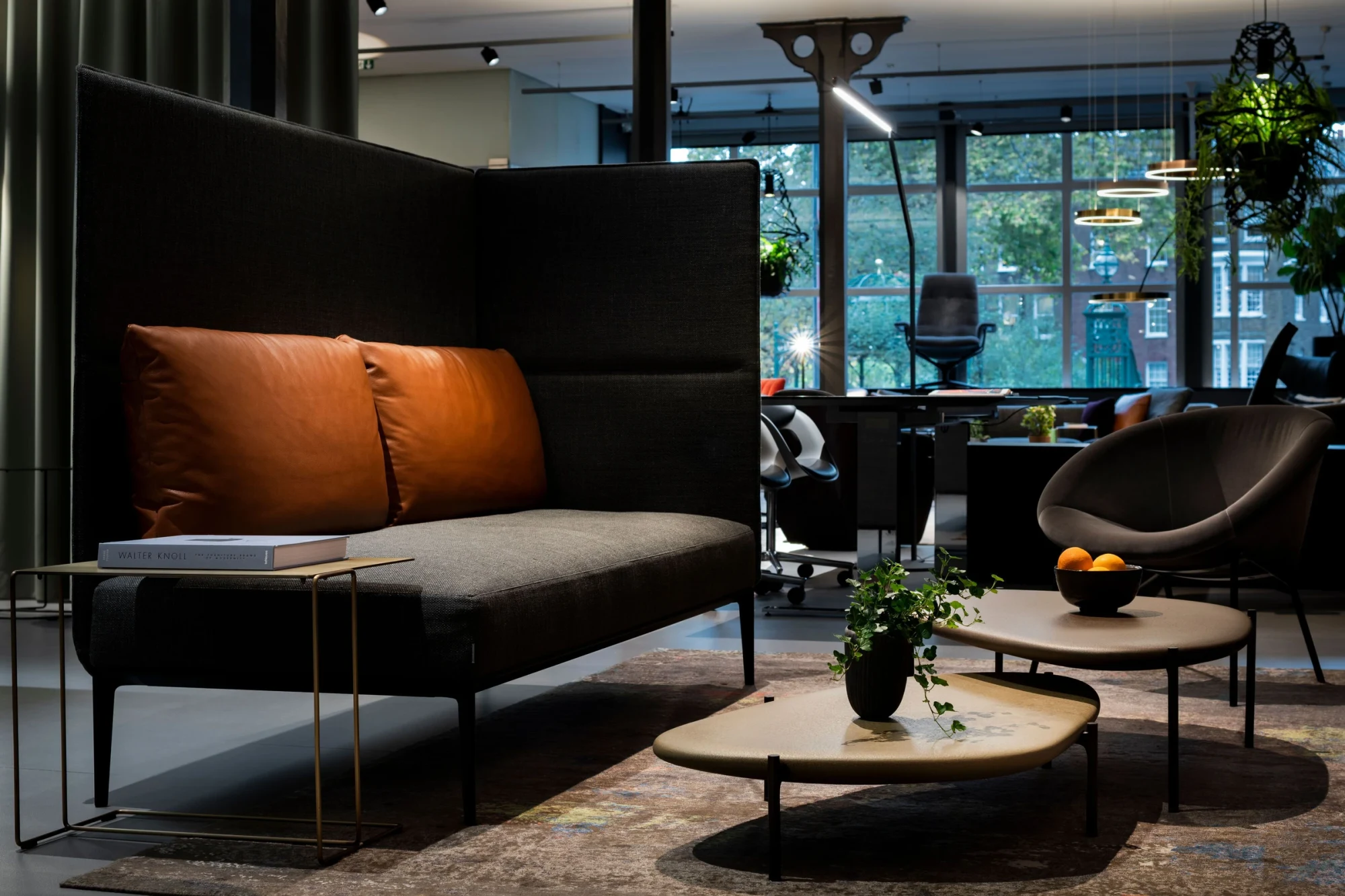 A sofa with a high back panel, a low table and an armchair in the London brand space