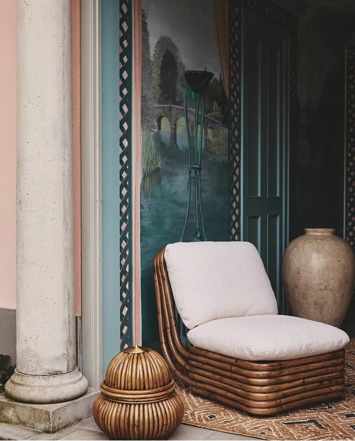 GUBI rattan lounge chair beside a column and vase