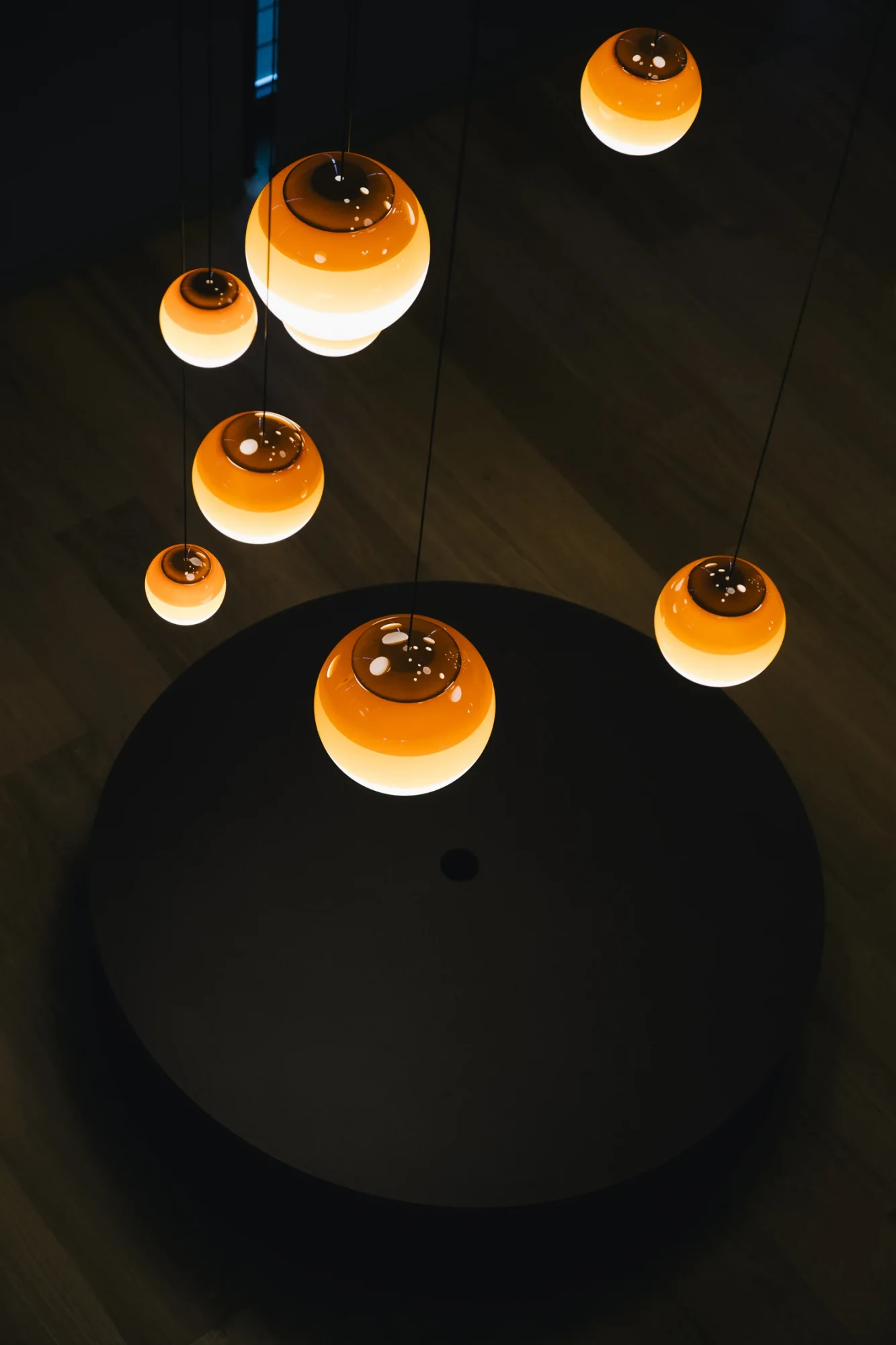 Marset pendant lamps with amber glass globes hanging in a dark room