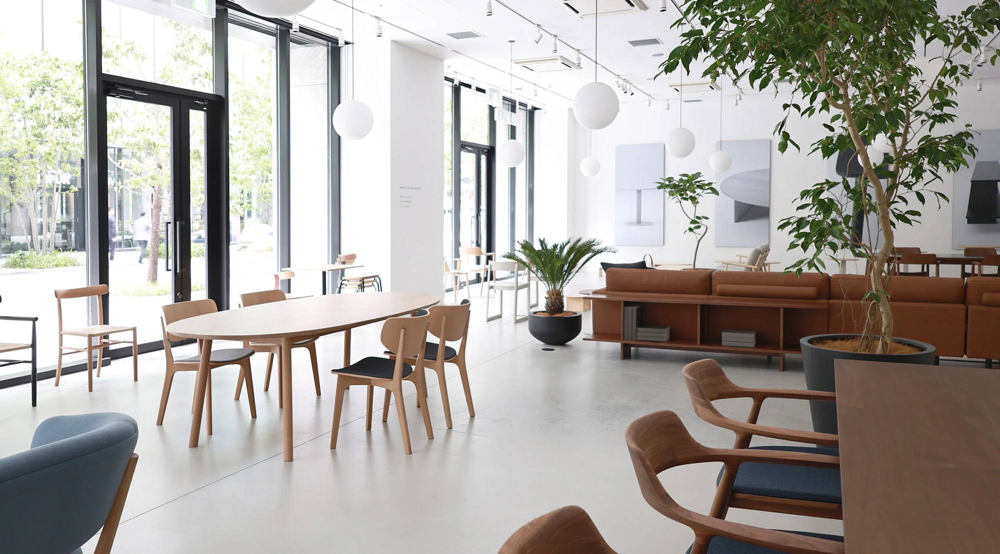 The Osaka showroom with tables, chairs and a sofa in a bright room with a tree