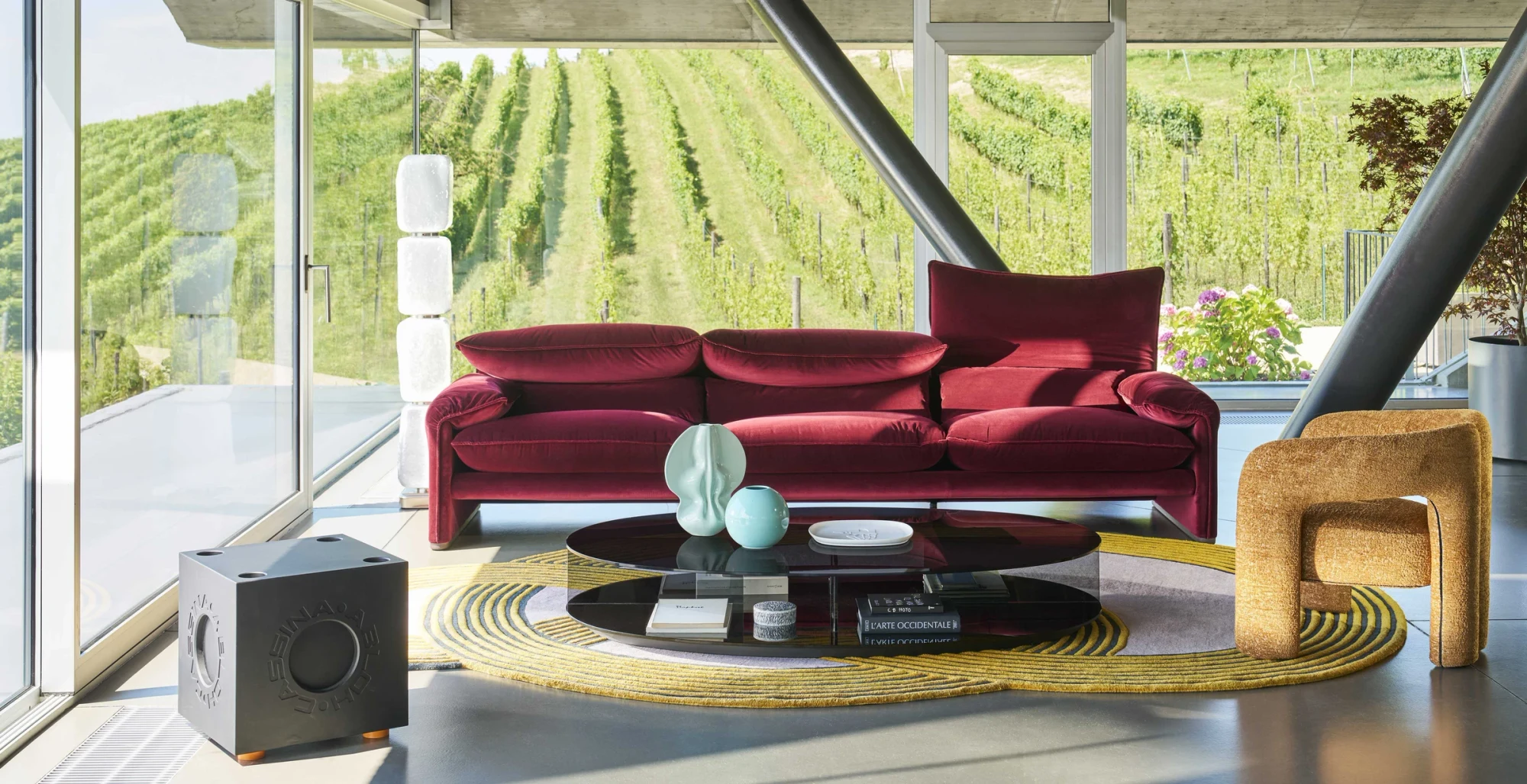Red Maralunga sofa in a living room with a vineyard view