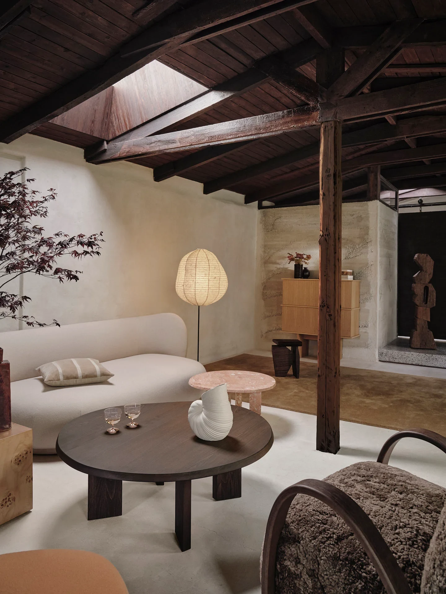 Living room with a rounded sofa, coffee table and armchair under exposed timber beams
