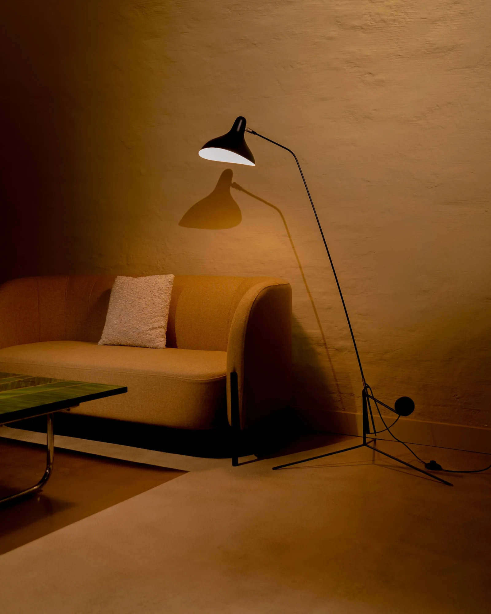 Mantis floor lamp beside a sofa in a warmly lit room