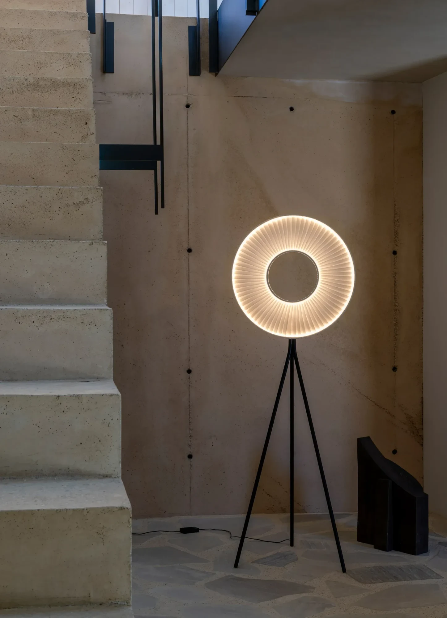 Iris tripod floor lamp beside a stone staircase