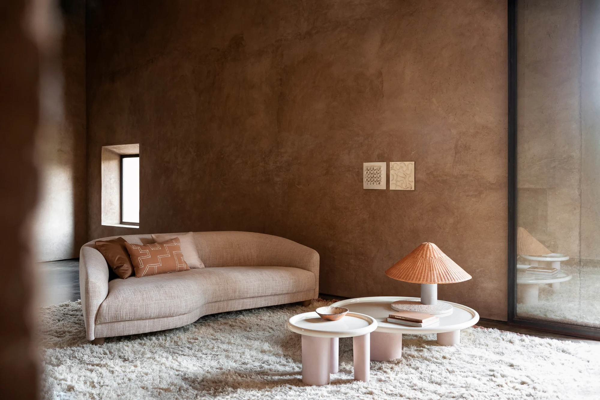 A curved sofa with low tables and a lamp in a large room with a rug