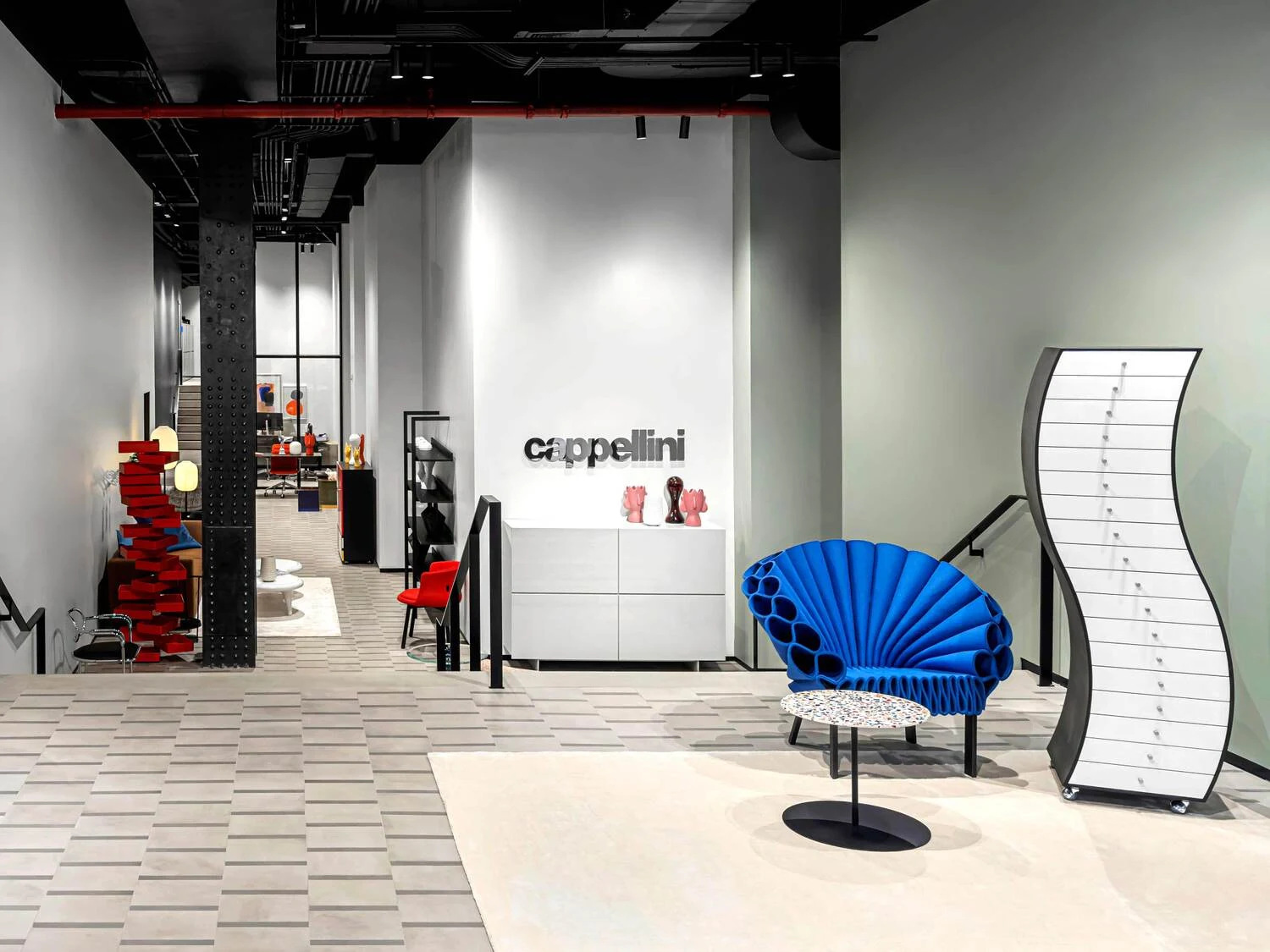 Cappellini showroom with a blue fan-backed armchair and a display cabinet