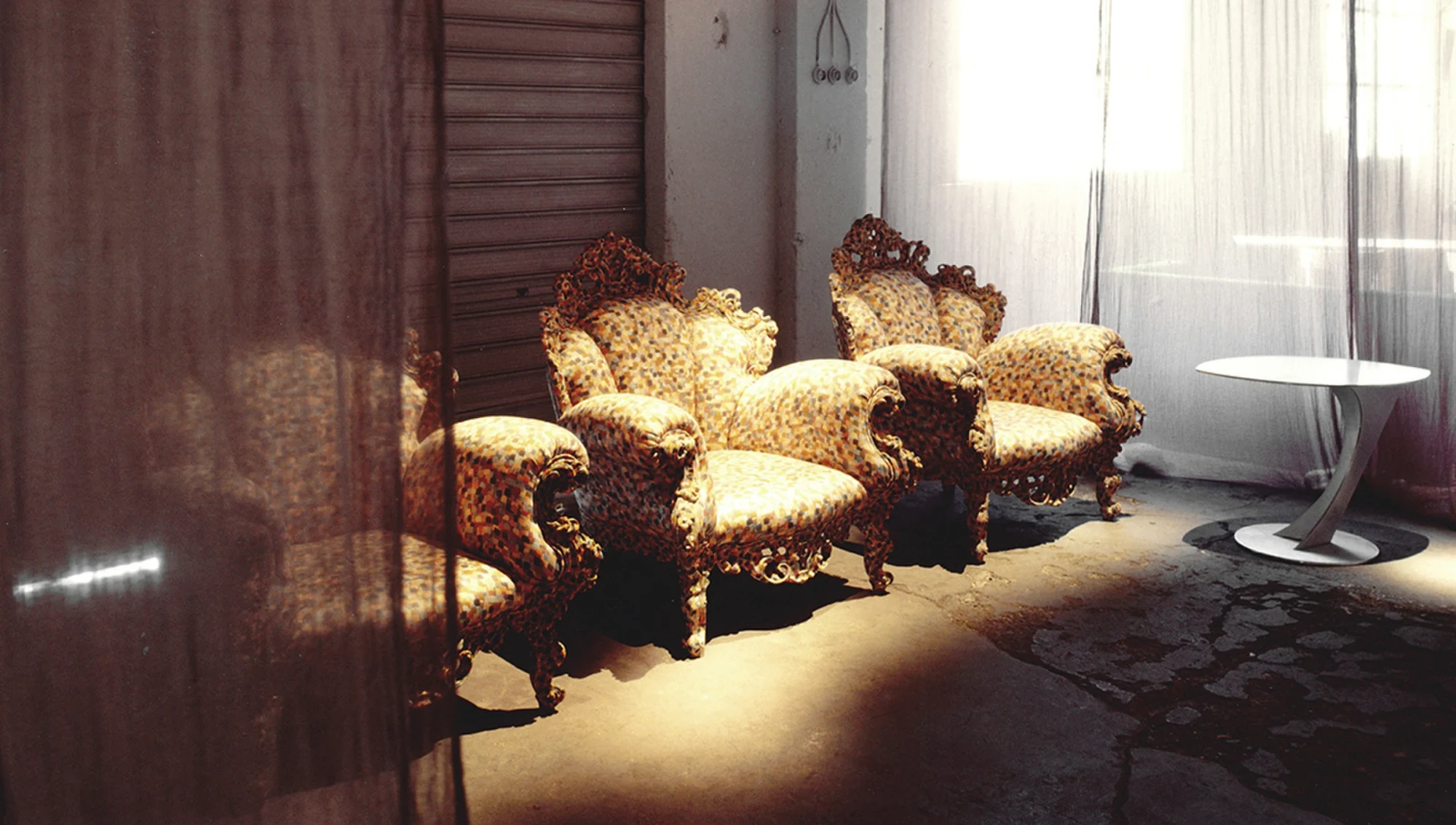 Ornate upholstered armchairs and a side table in a dimly lit room