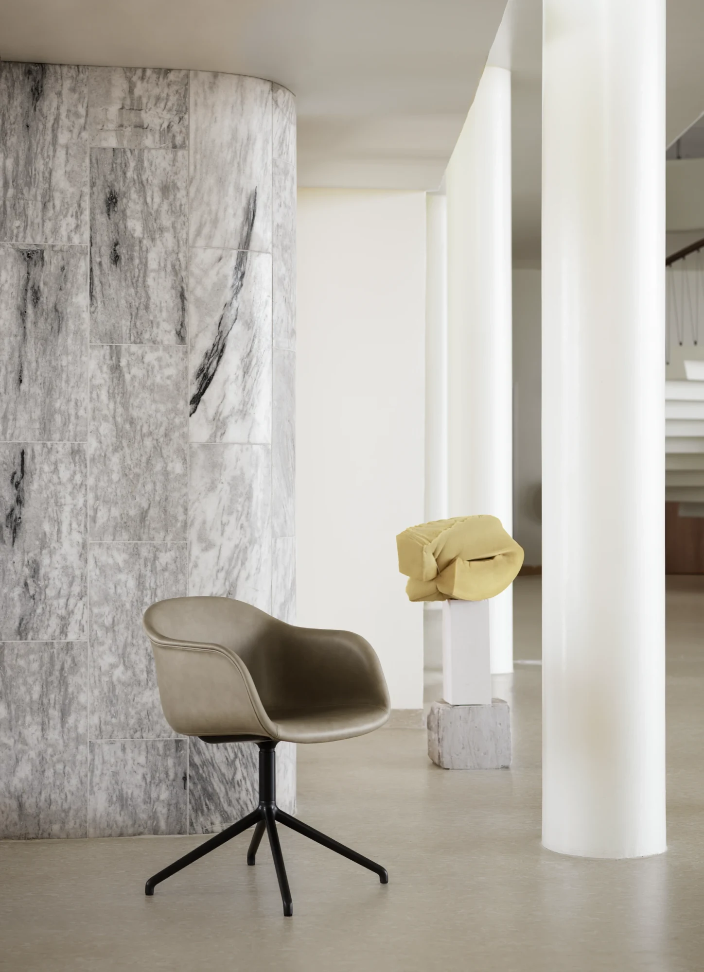 Muuto Fiber Armchair swivel chair beside a curved wall