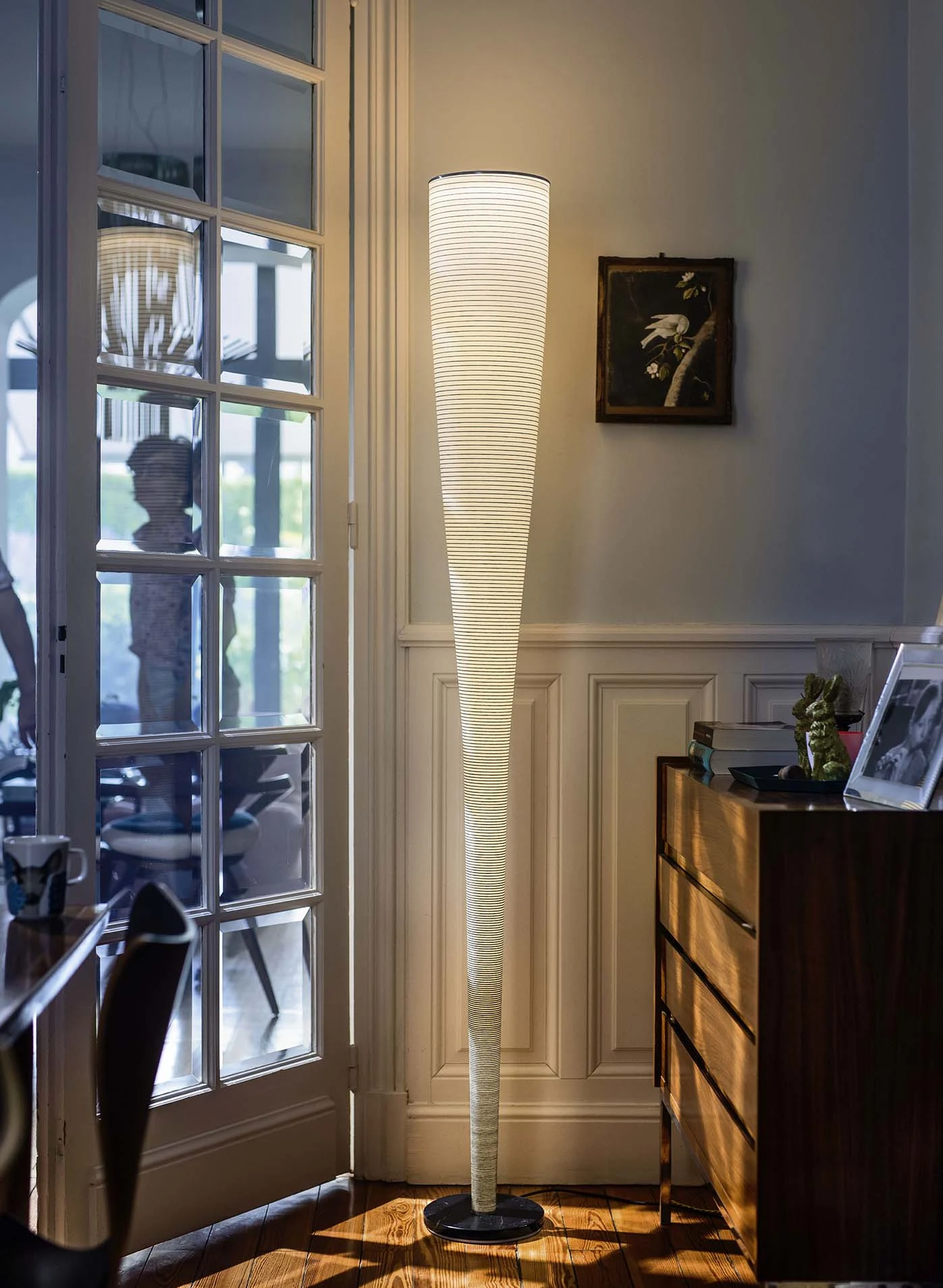 Tall white floor lamp beside a glazed door