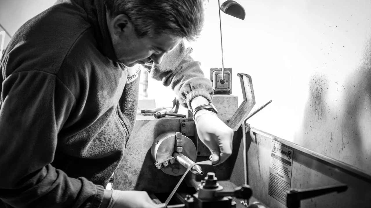Craftsman machining a metal part at a lathe