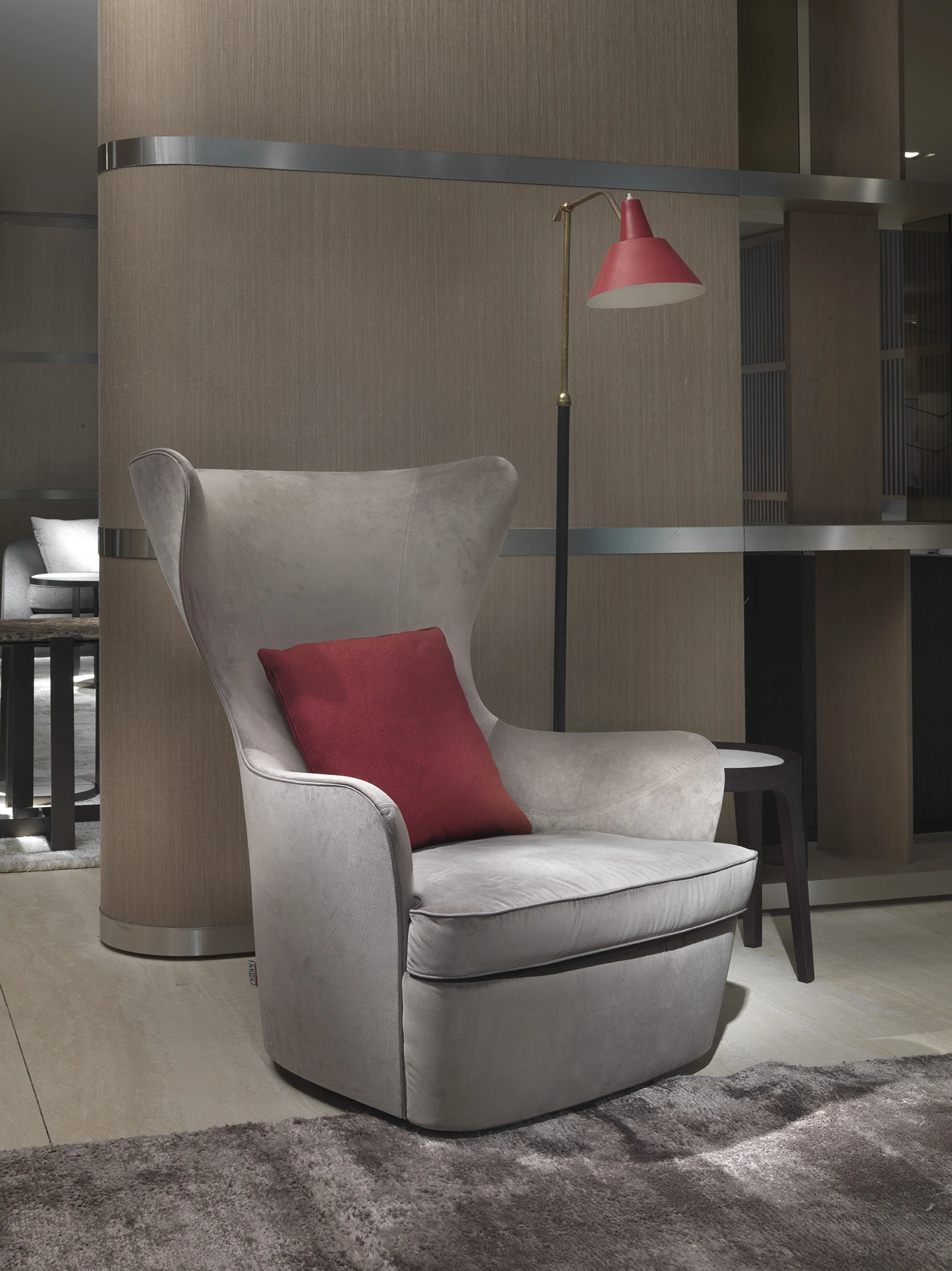Wing armchair with a red cushion in a showroom setting with a floor lamp