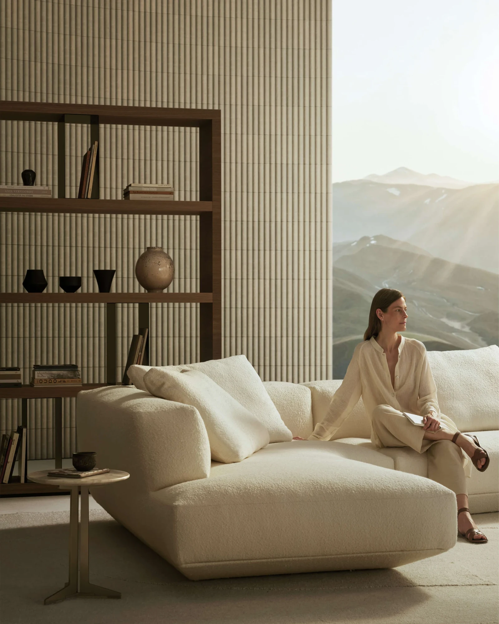Woman seated on a Loungescape sofa in front of shelves and a mountain view