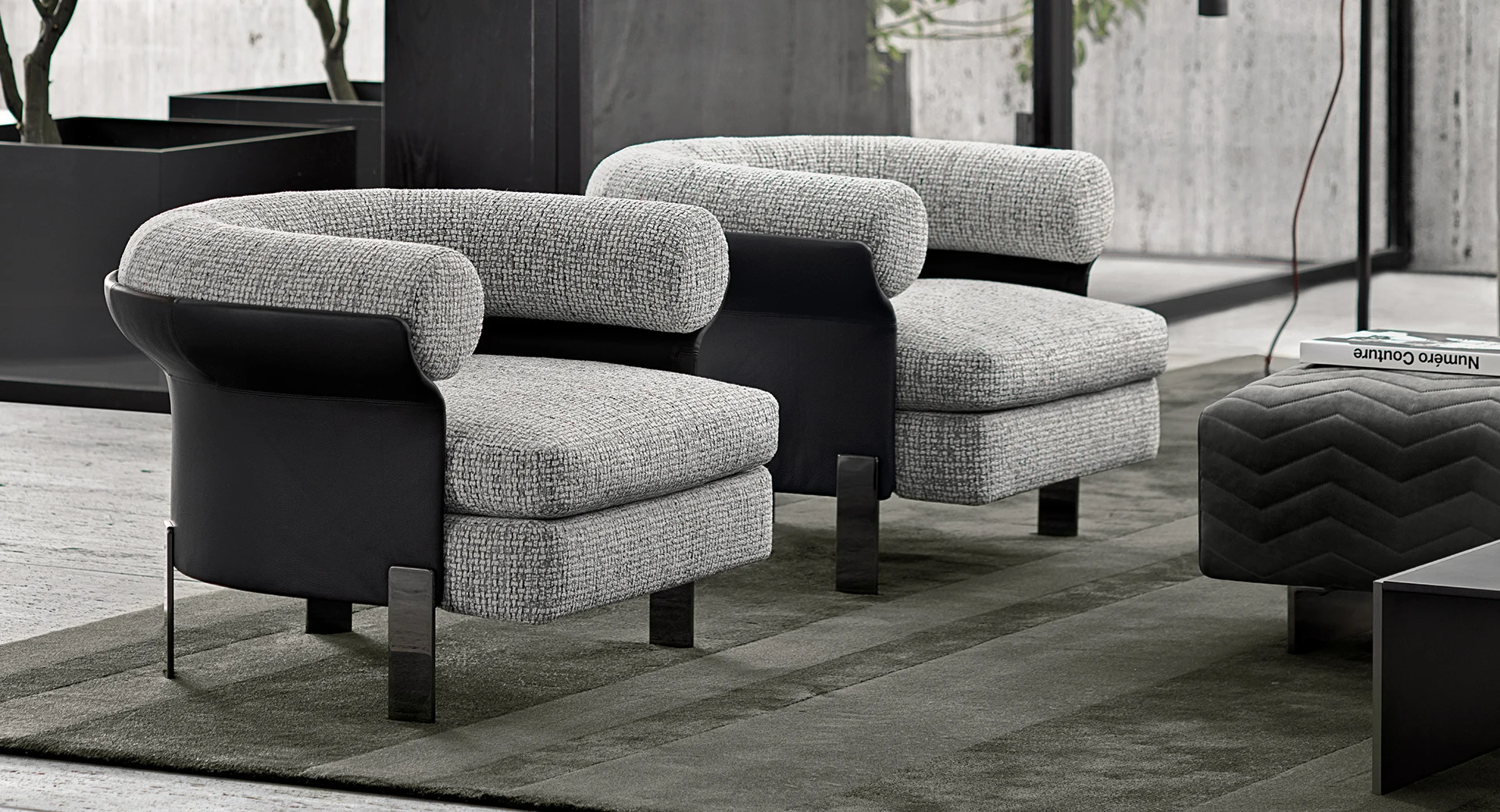 Two armchairs with a rolled upper edge beside an ottoman, official Minotti photo
