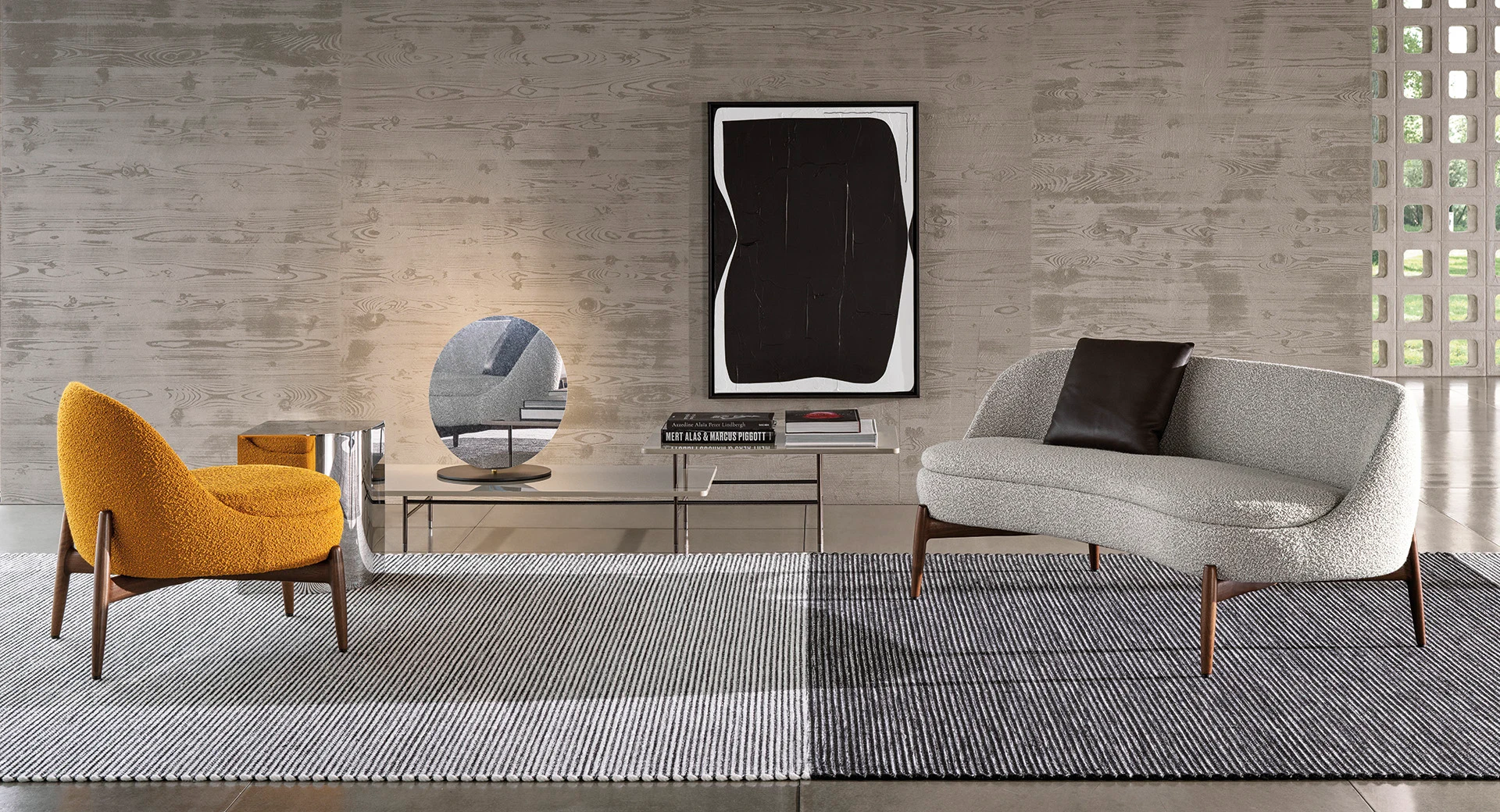Sendai armchair and sofa on slender legs in front of a wall with a large artwork, official Minotti photo