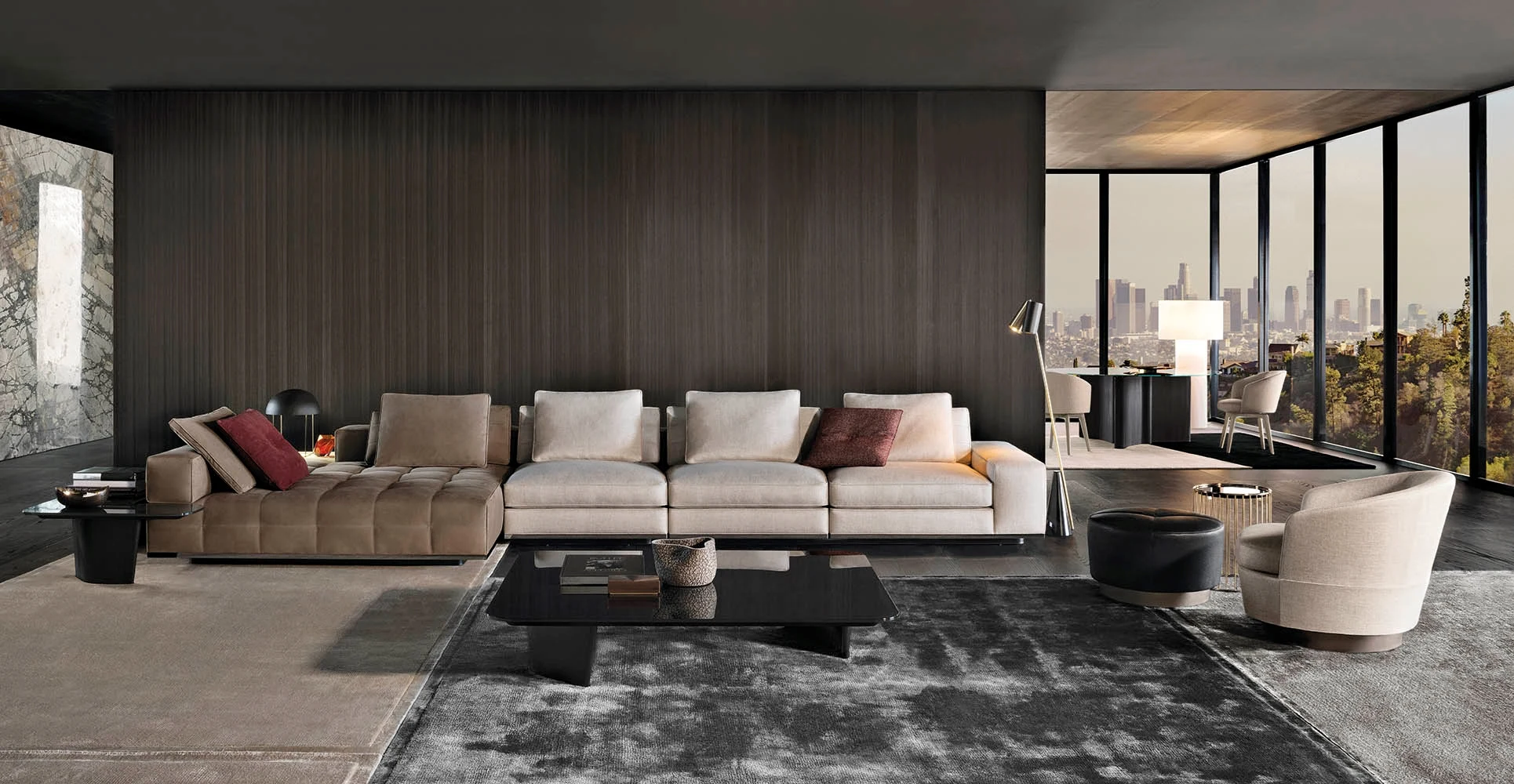 A long sofa with a chaise element at the left, a low table and an armchair in a room with a view over a city, official Minotti photo