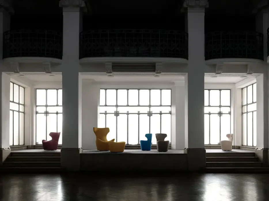 Armchairs in different covers in a hall with tall windows, official photo