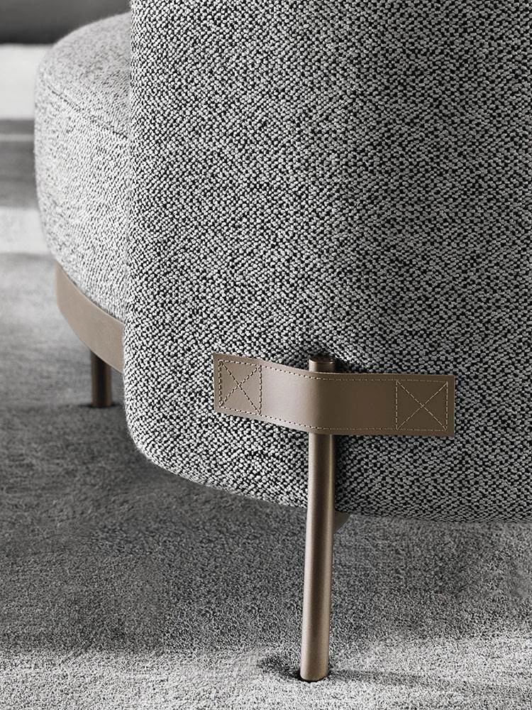 Close view of a metal foot with a strap around it, beside an upholstered seat, official Minotti photo
