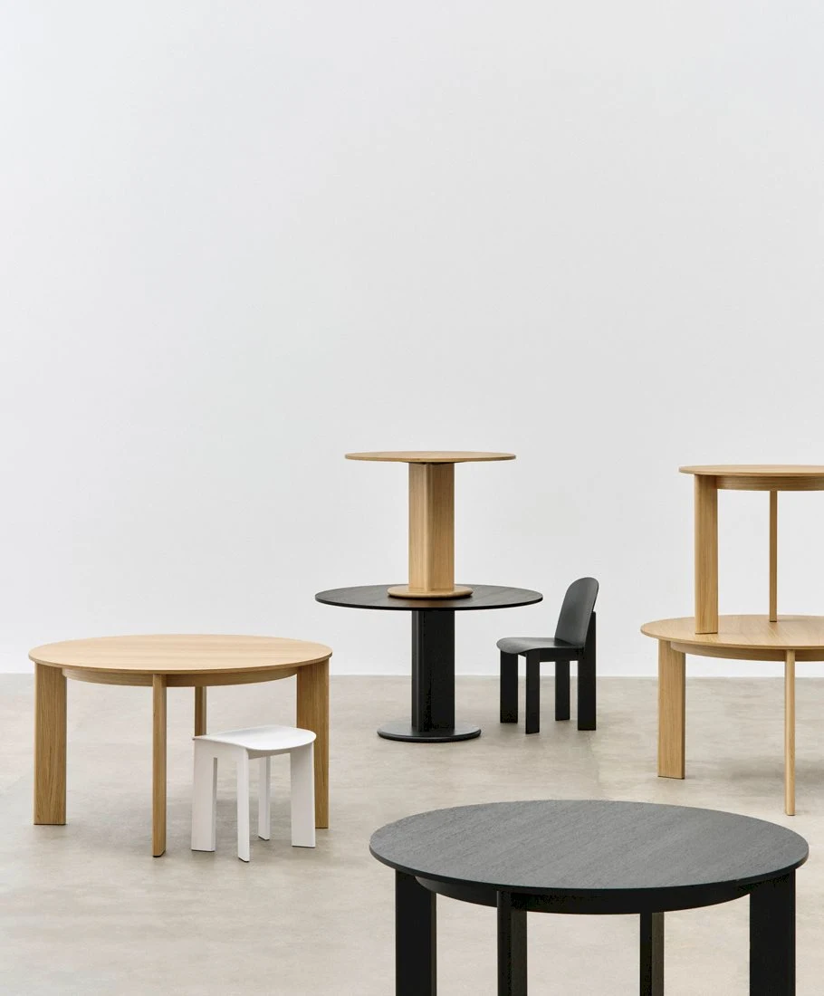 Round tables of different sizes with a chair and a stool standing on a plain floor