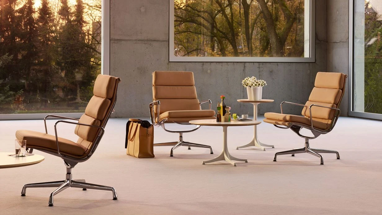 Three padded chairs with aluminium frames around a low round table, in a room