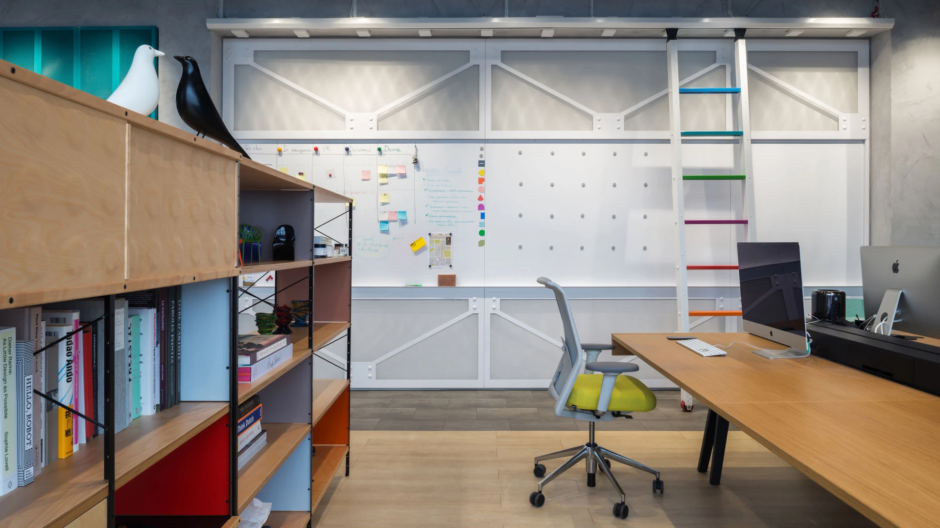 An office with a desk and a shelving unit at the left edge