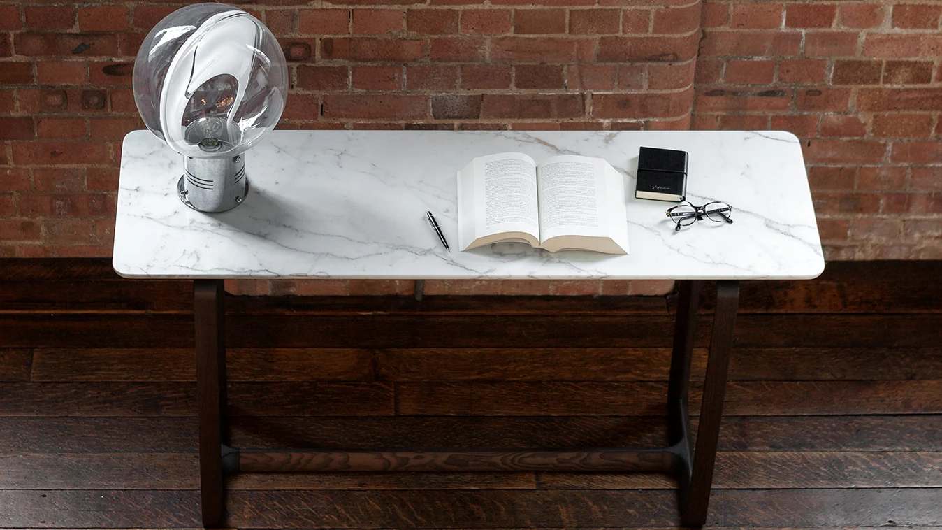 Fidelio console with an open book and a table lamp on its top