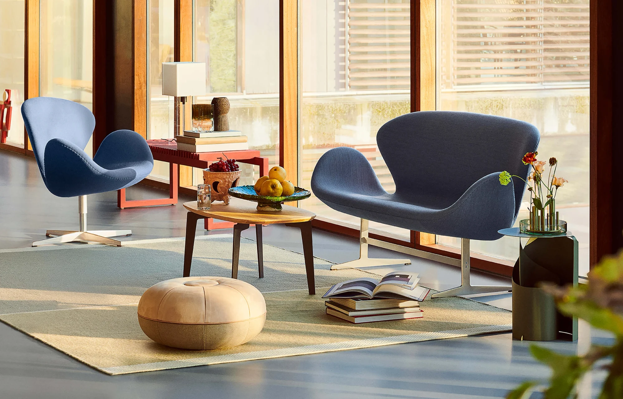 Swan sofa and Swan lounge chair with blue upholstery in a room with a low table and a pouf
