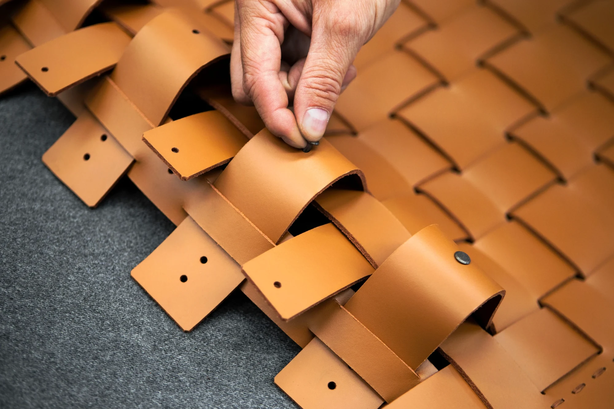 Hands weaving strips into a basket-like pattern