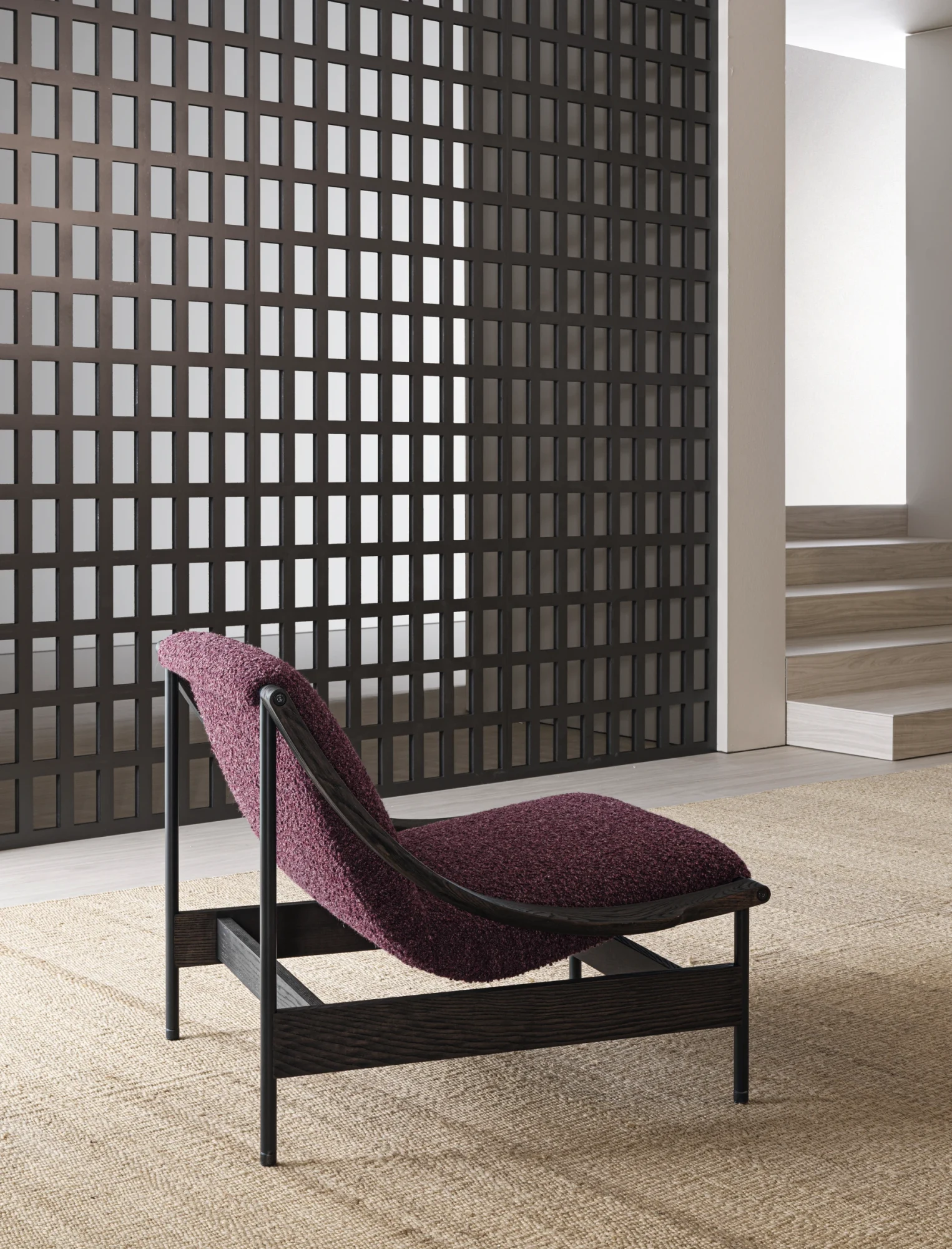 A Lia armchair seen from the side in front of a lattice screen, with steps at the right
