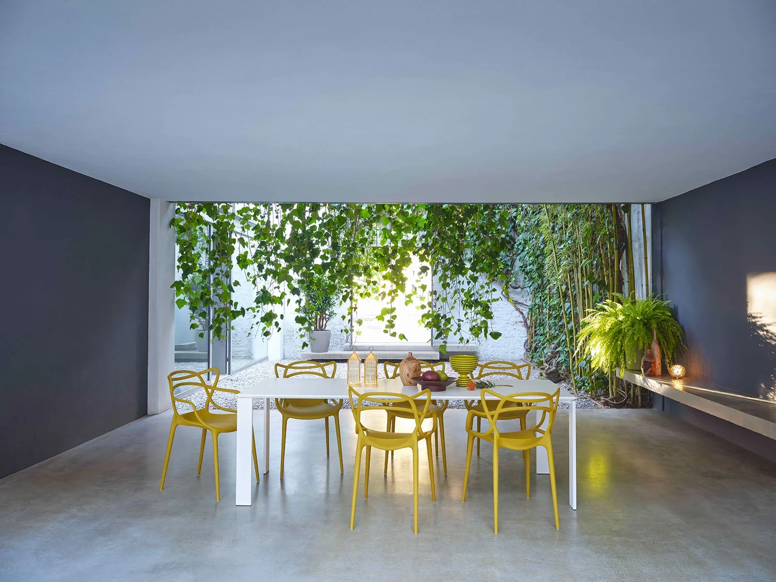 Masters chairs around a table in a room opening onto greenery
