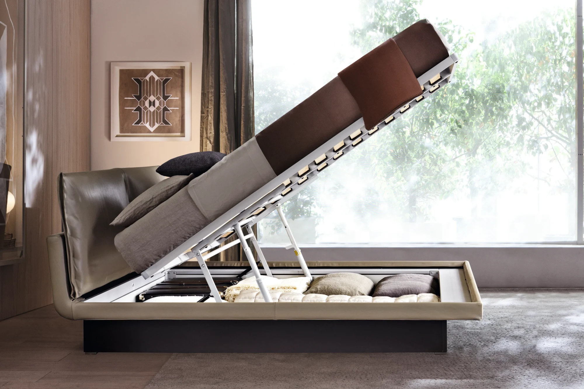 A bed with the storage container raised on its lifting mechanism, beside a large window