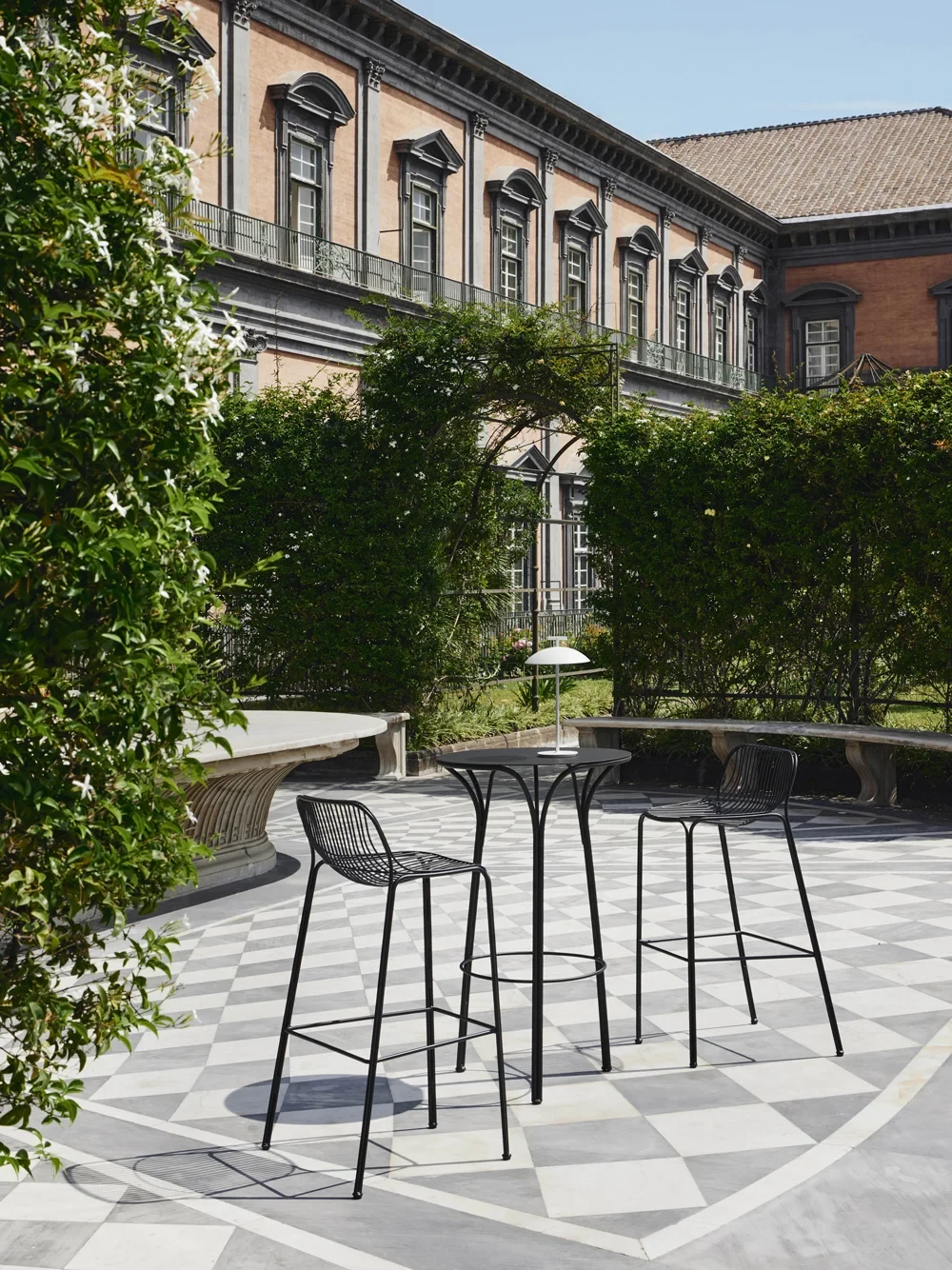Two stools and a high table outdoors in front of a building