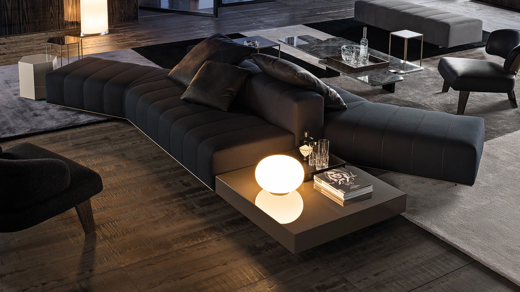 Long sofa composition with a side table and lamp in a dark room, official Minotti photo