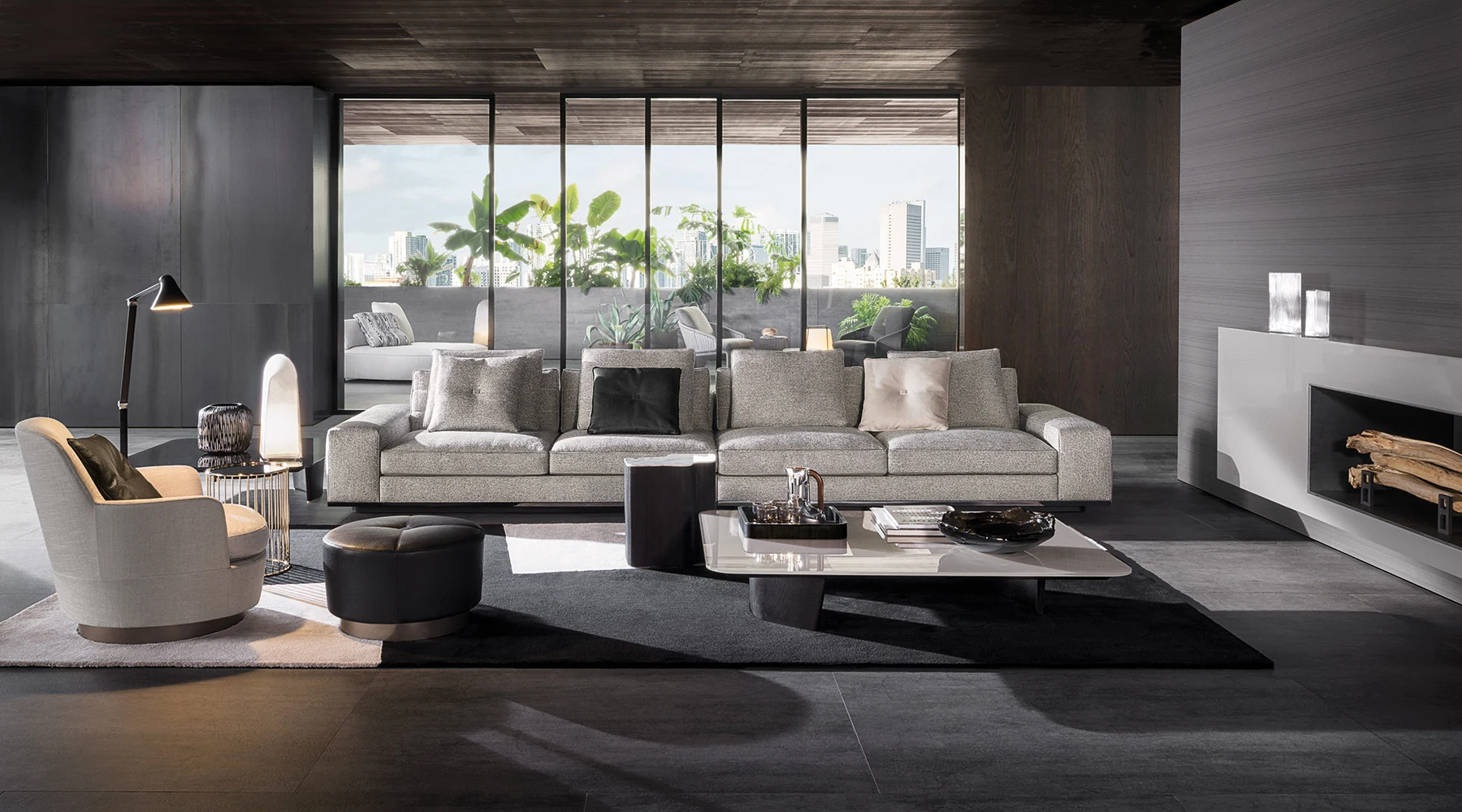 A sofa facing a low table, with an armchair and an ottoman at the left, in a room with a window wall, official Minotti photo