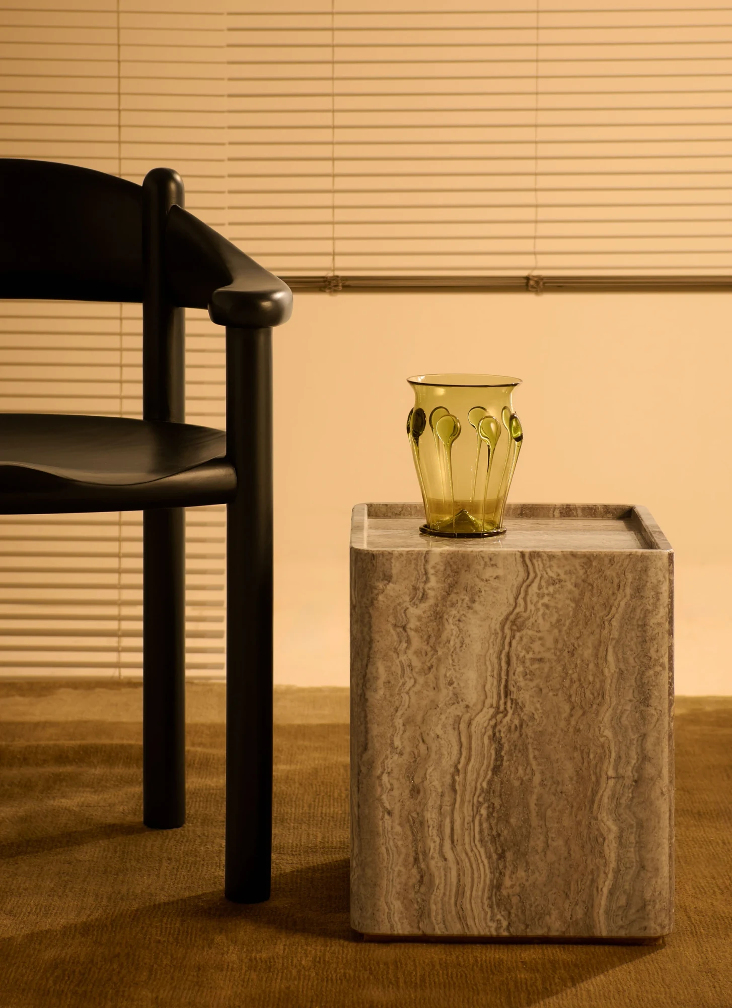 Small square side table beside a chair, with a glass vase on its top