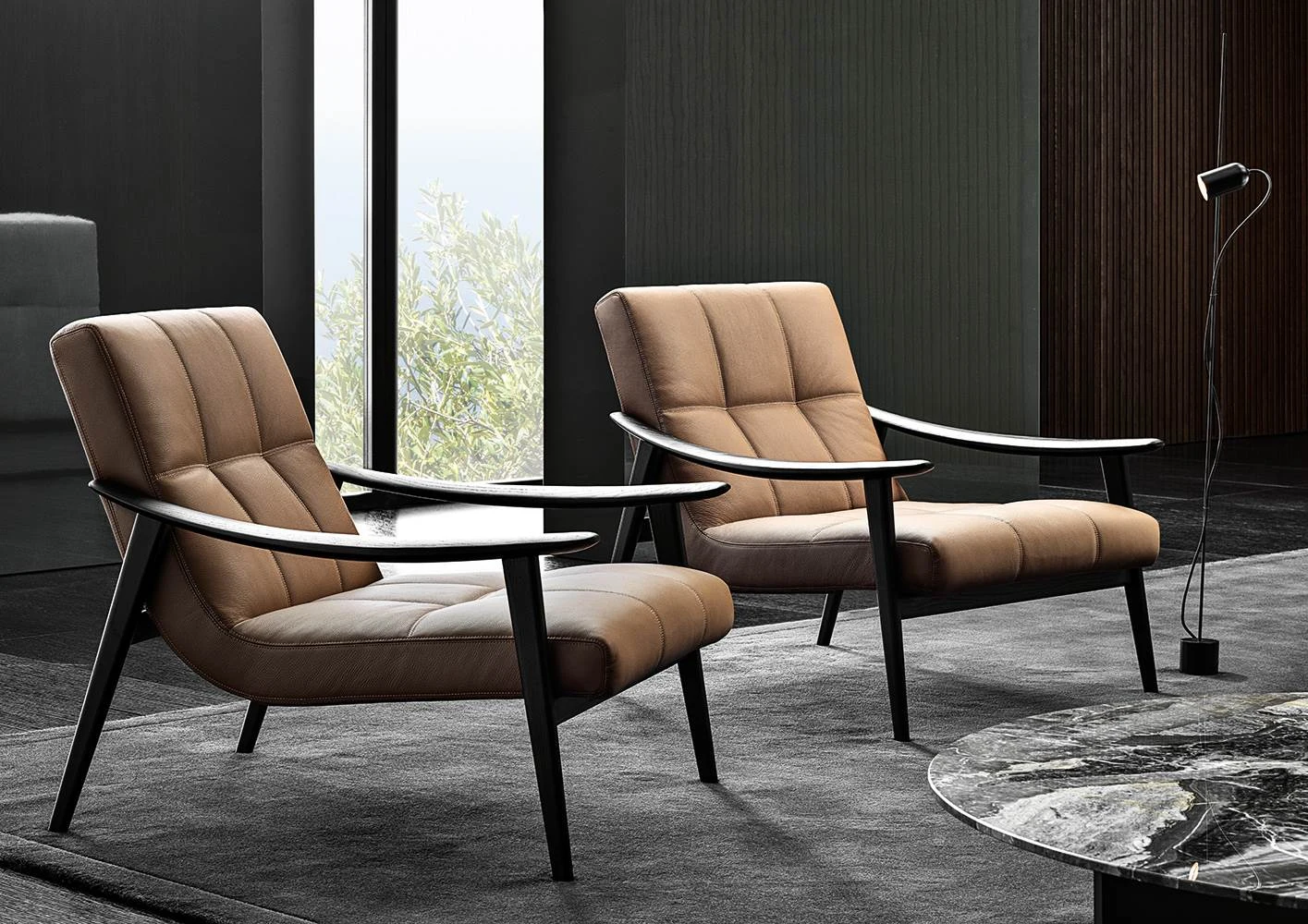 Two armchairs with long curved armrests in a room with a large window