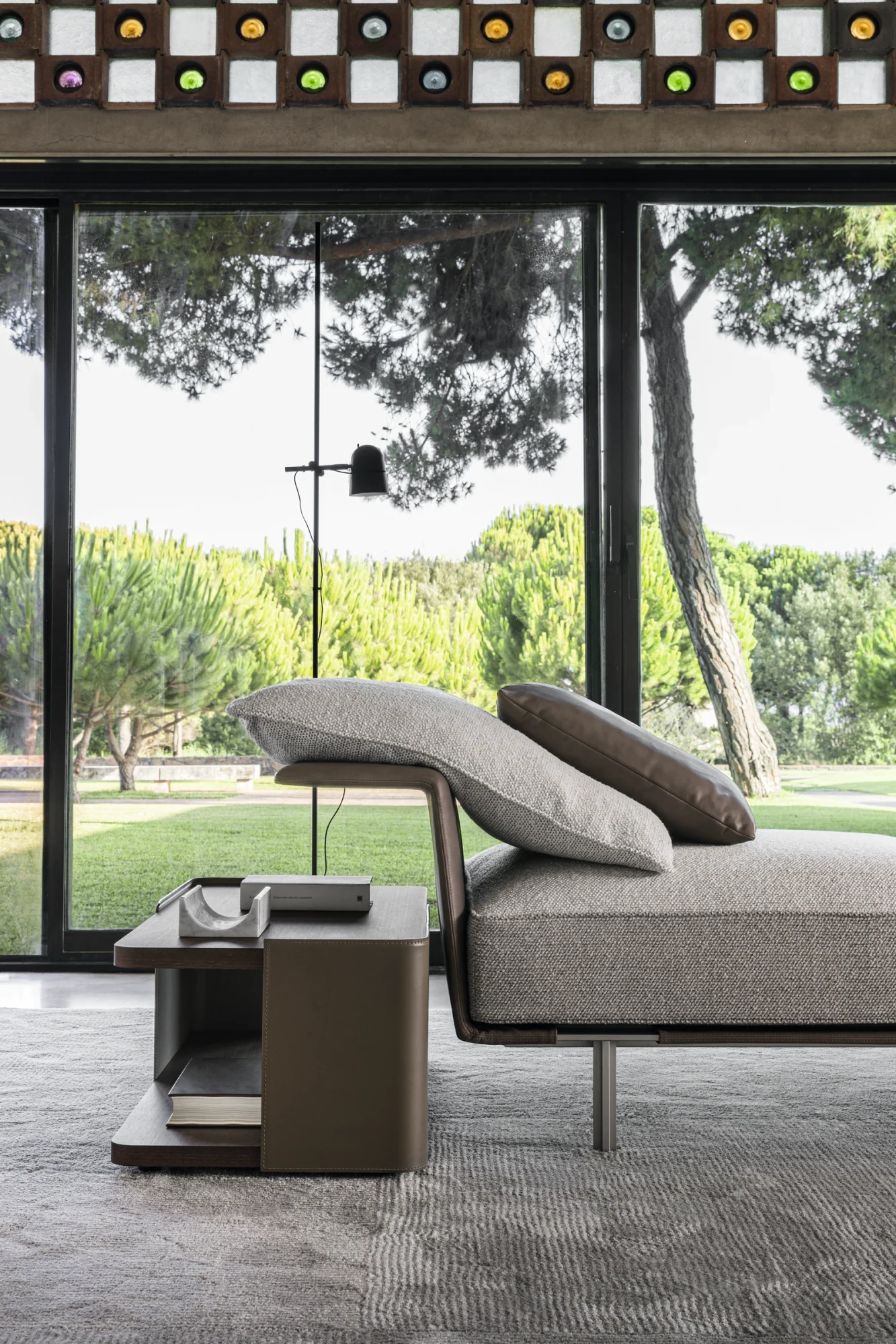 Sofa with a chaise end and a headrest cushion in a room with trees outside