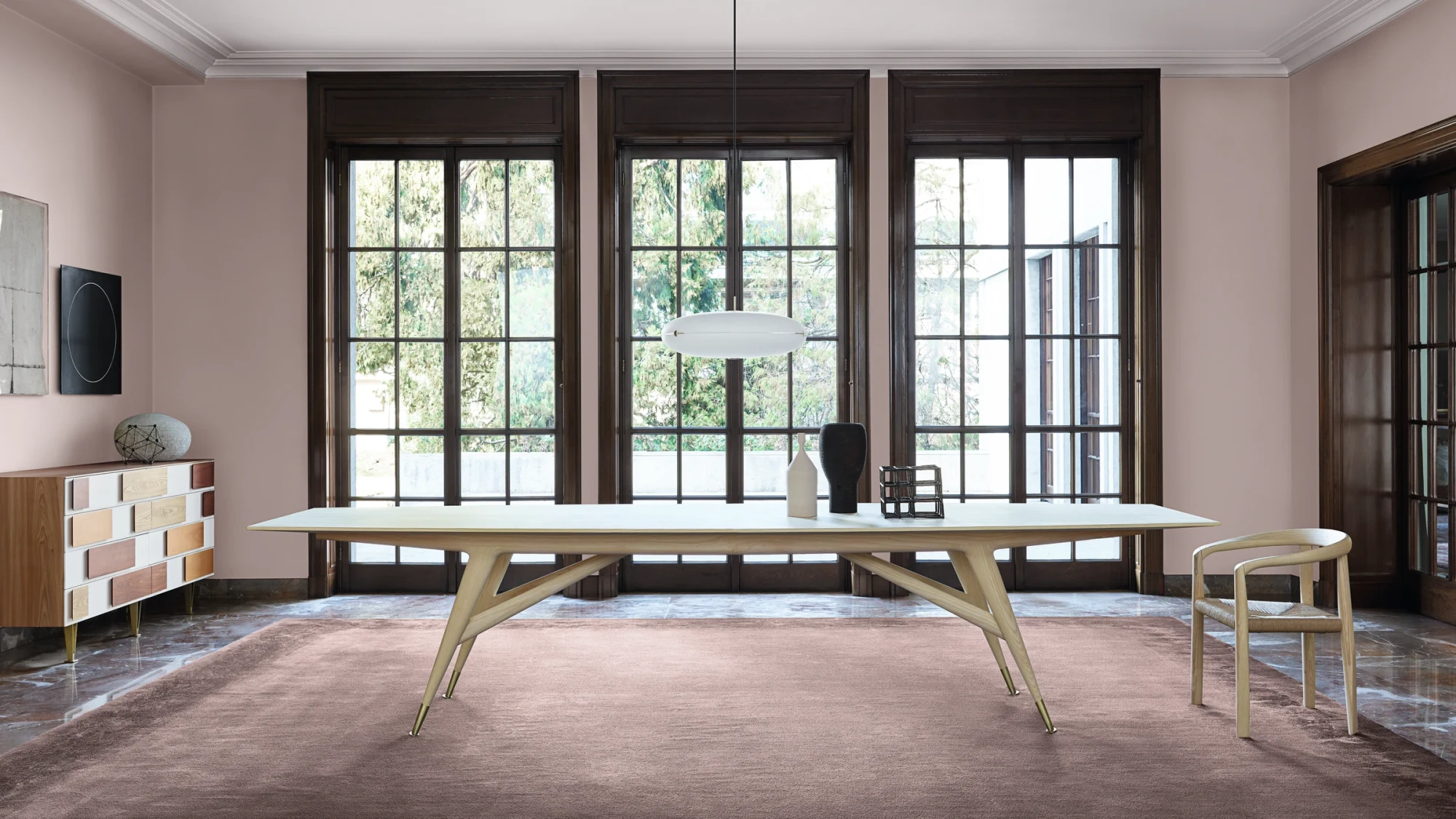 Long table with a chair at its end in a high room with a patterned floor covering