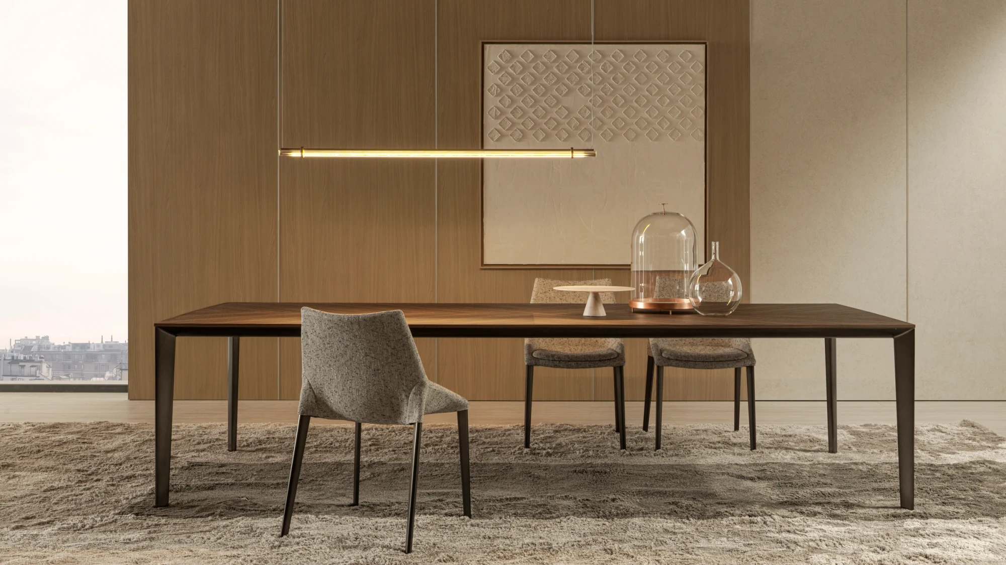 Rectangular table with a long thin top, chairs at its edge and a light fixture above, in front of a wall