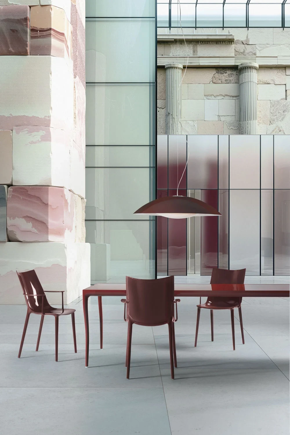 Burgundy chairs with arms around a table beneath a pendant lamp
