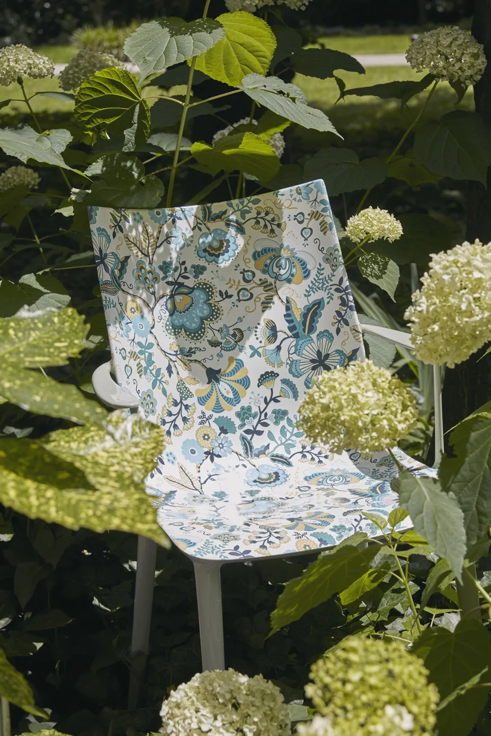 Chair with a floral-patterned seat among pale flowers and leaves