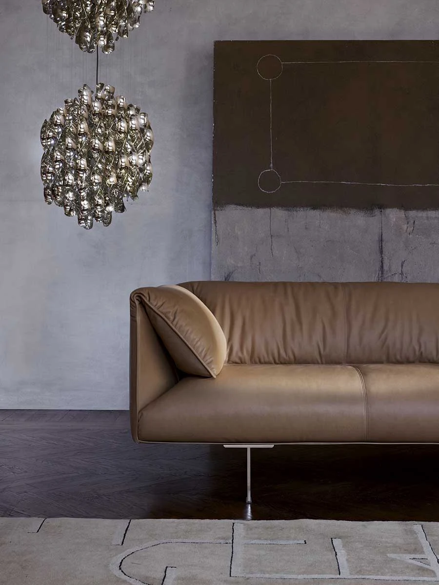 Brown sofa against a grey wall with a hanging spherical lamp above it