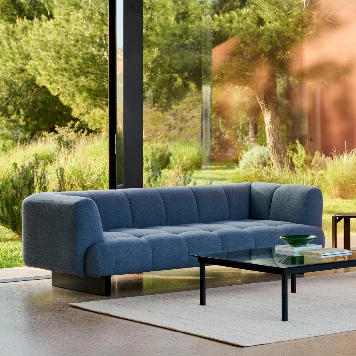 Quilton Lift 3 places avec une table basse et un tapis devant une paroi vitrée