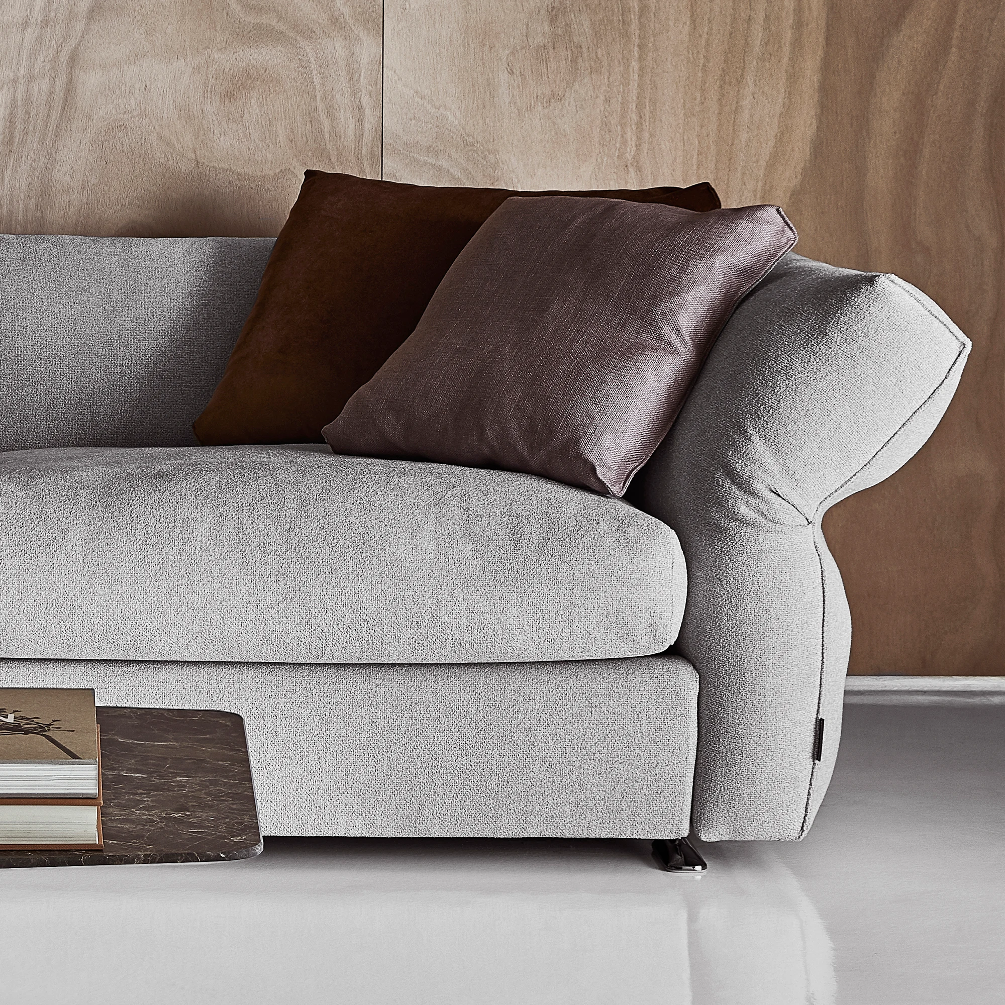 Close view of a sofa seat and armrest with two cushions beside a low table