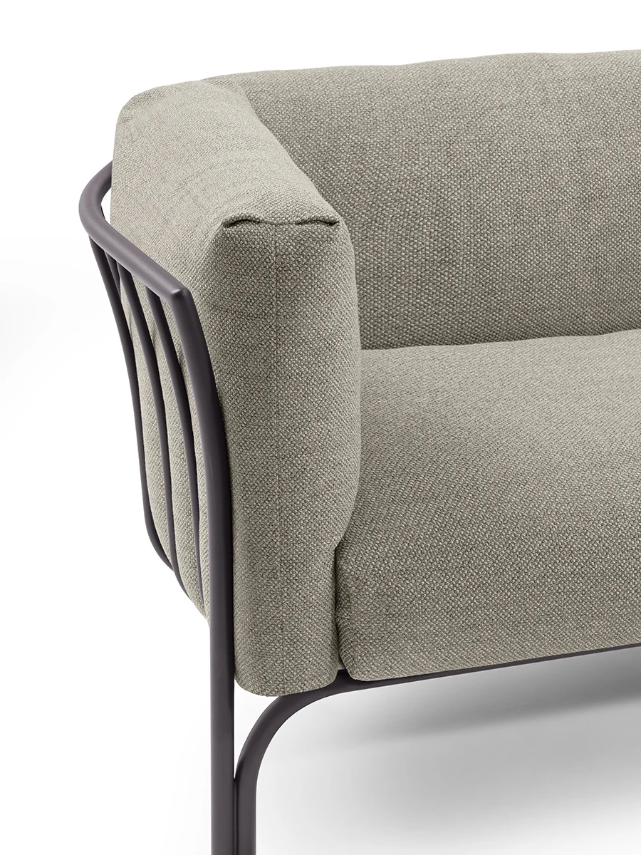 Close view of a sofa corner with slender metal uprights along the back and a padded arm