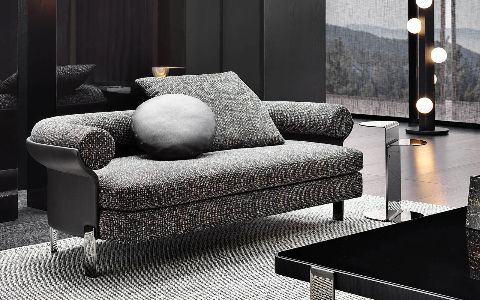 Mattia sofa with a round cushion in front of a window with mountain views, official Minotti photo