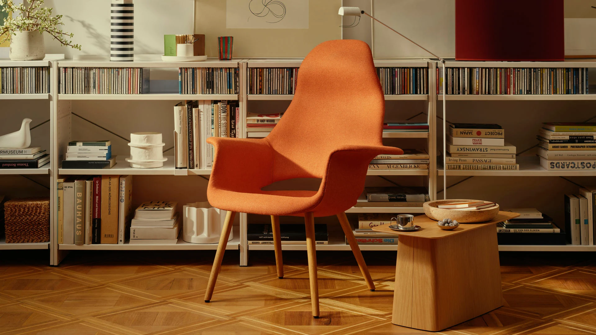 A chair in front of shelves with a wooden side table beside it