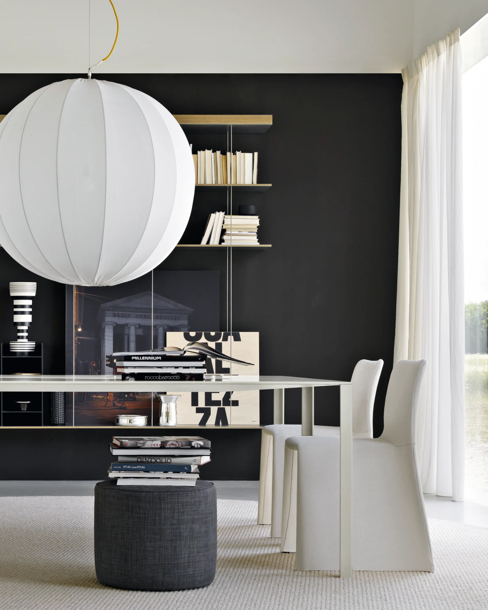 Glove chairs at a long table, with a round hanging pendant and shelving behind